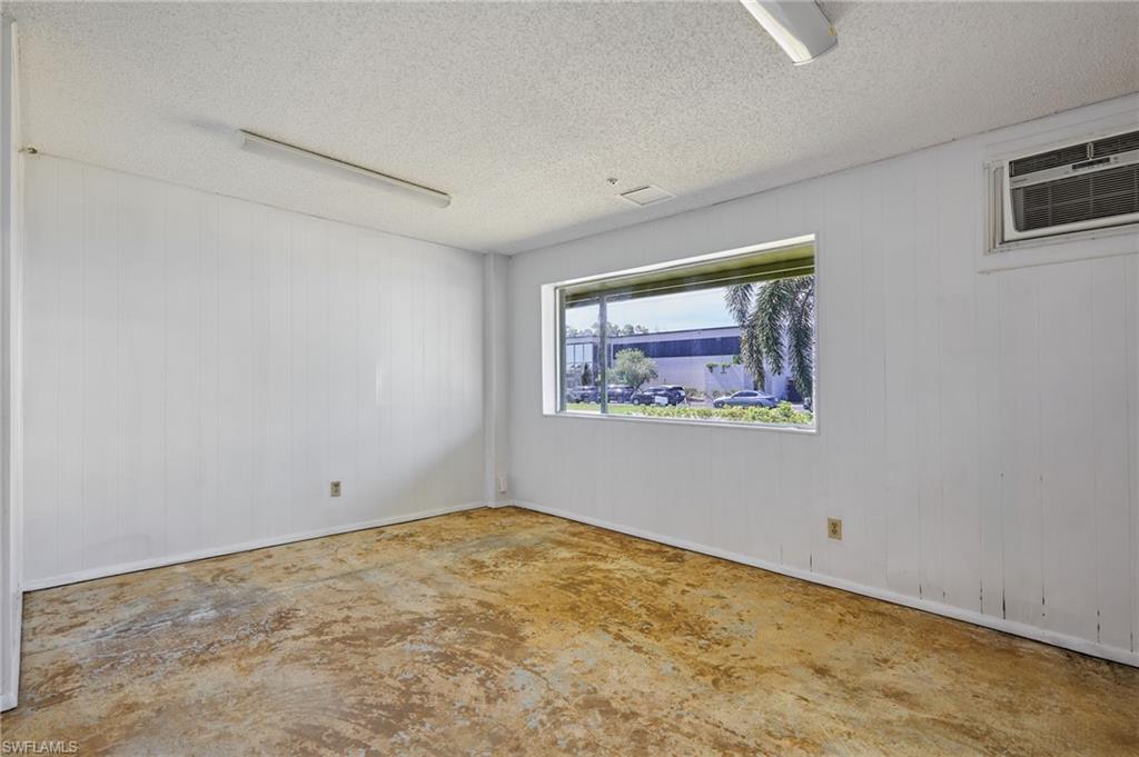 Unfurnished room featuring wood walls, a textured ceiling, concrete flooring, and a wall mounted air conditioner