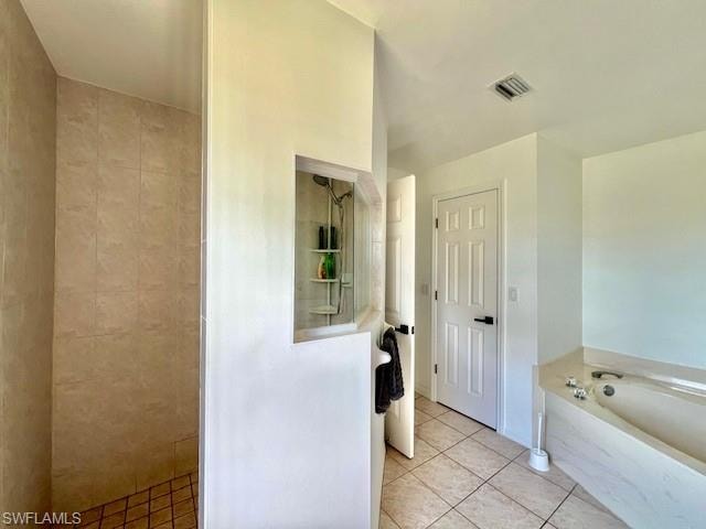 Bathroom with light tile patterned floors, a garden tub, and a tile shower