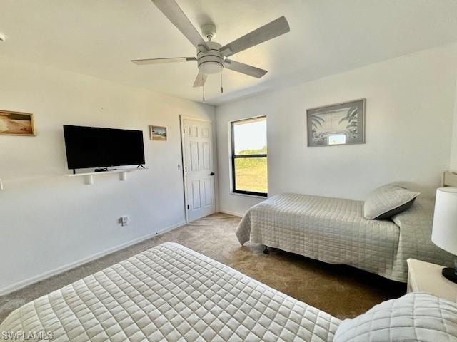 Carpeted bedroom with ceiling fan and baseboards