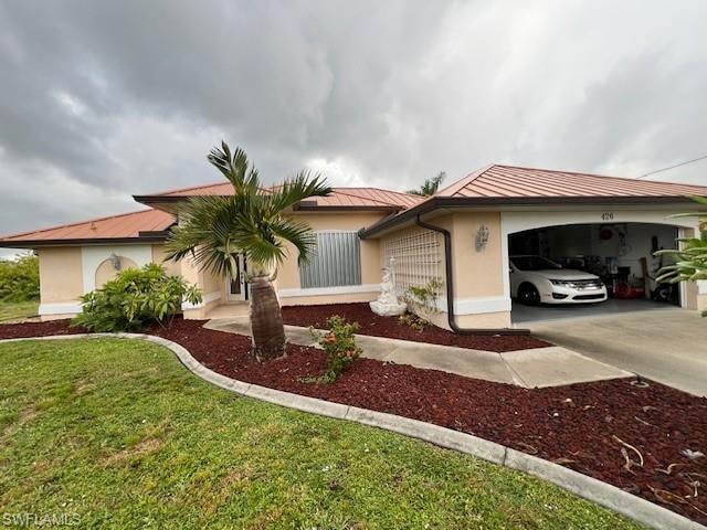 View of front of house featuring stucco siding, a front yard, driveway, and a metal roof