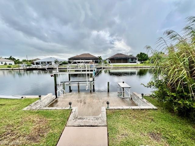 Dock with boat lift, a water view, and a lawn