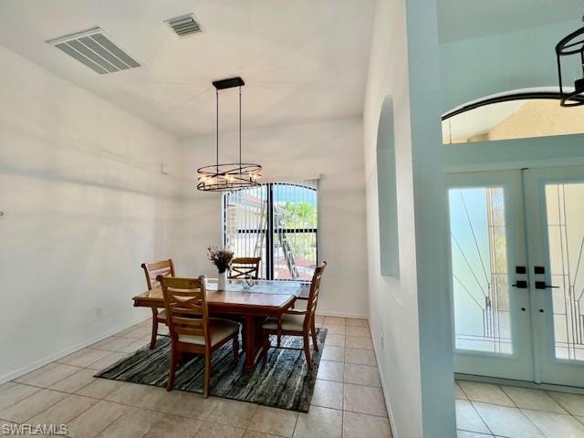 Dining area with french doors, light tile patterned floors, and a chandelier