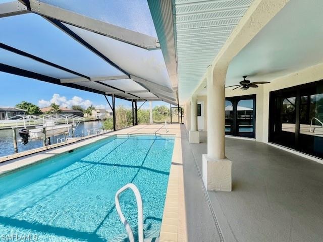 Outdoor pool with a patio area, a water view, ceiling fan, boat lift, and a dock