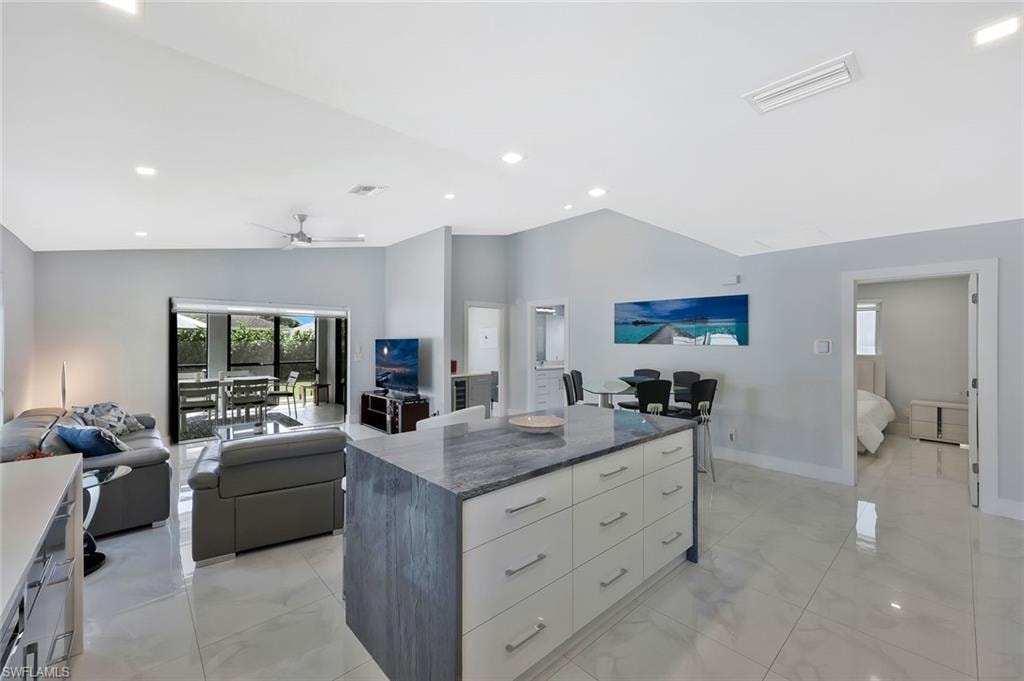 Kitchen featuring a center island, open floor plan, light marble finish flooring, dark stone countertops, and modern cabinets