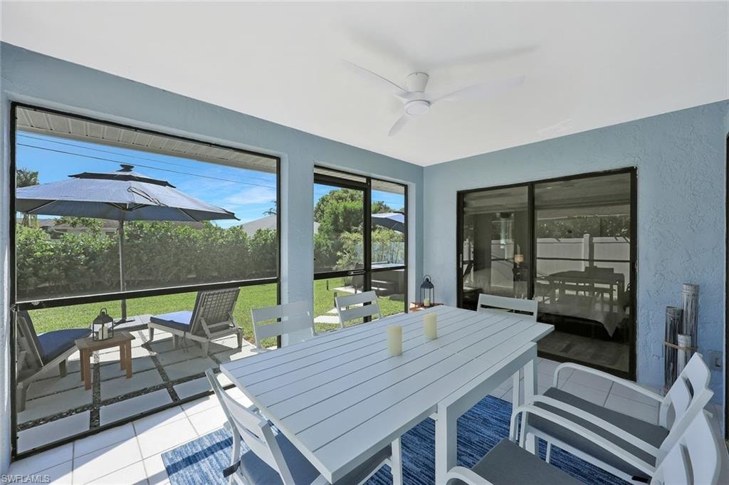 Sunroom featuring outdoor dining area, a ceiling fan, and a patio area