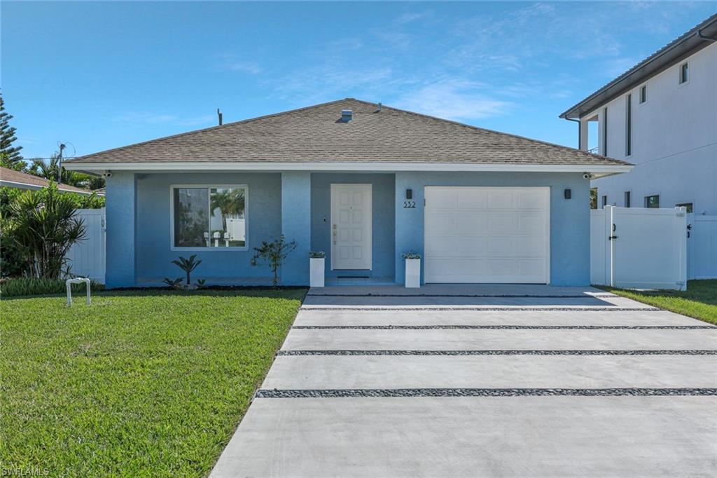 Ranch-style house featuring a shingled roof, stucco siding, concrete driveway, an attached garage, and a gate