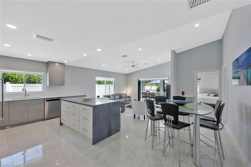 Kitchen with dark stone counters, healthy amount of natural light, gray cabinetry, backsplash, and recessed lighting