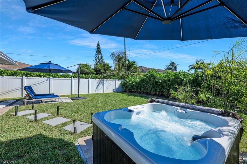 Fenced backyard featuring a hot tub and a patio area
