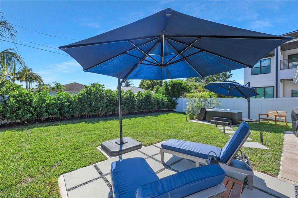 Fenced backyard with a patio area, a hot tub, and an outdoor hangout area