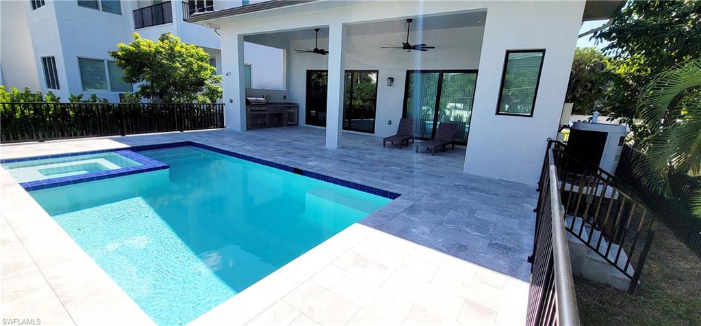 View of swimming pool with ceiling fan, area for grilling, a patio, and a pool with connected hot tub