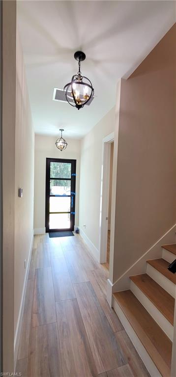 Foyer entrance featuring light wood-style floors, stairs, and a chandelier