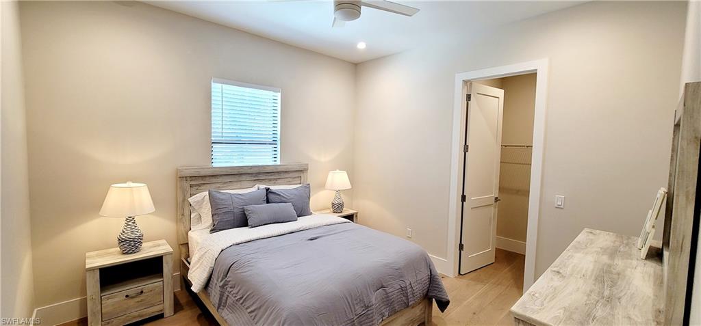 Bedroom with light wood-type flooring, a ceiling fan, and a walk in closet