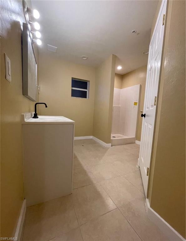 Full bath with a shower stall, light tile patterned floors, vanity, and recessed lighting