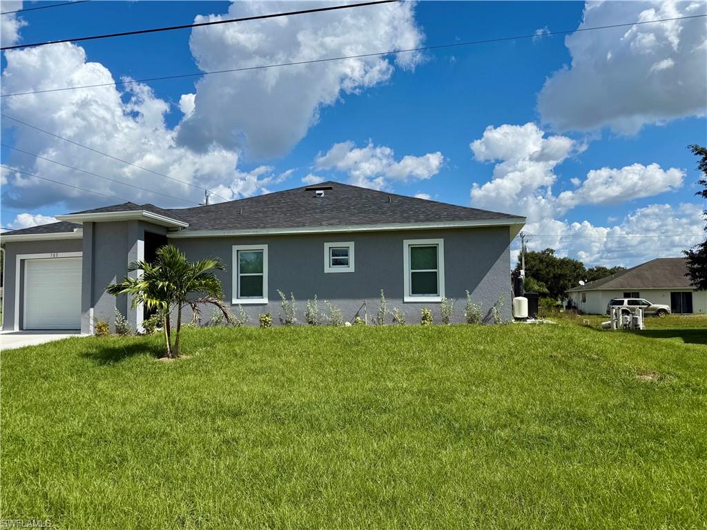 View of home's exterior with a yard, stucco siding, an attached garage, and a shingled roof