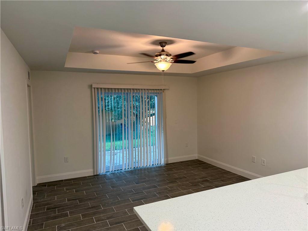 Spare room with a raised ceiling, wood tiled floors, and ceiling fan