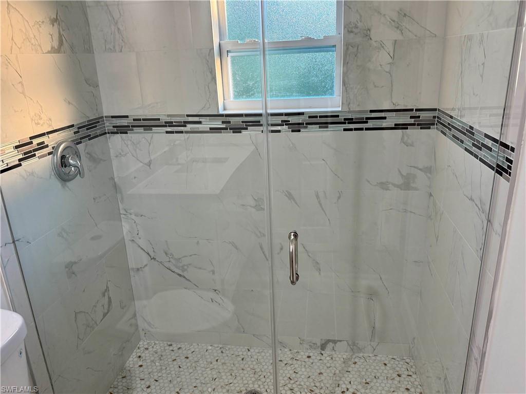 Bathroom featuring a marble finish shower and toilet