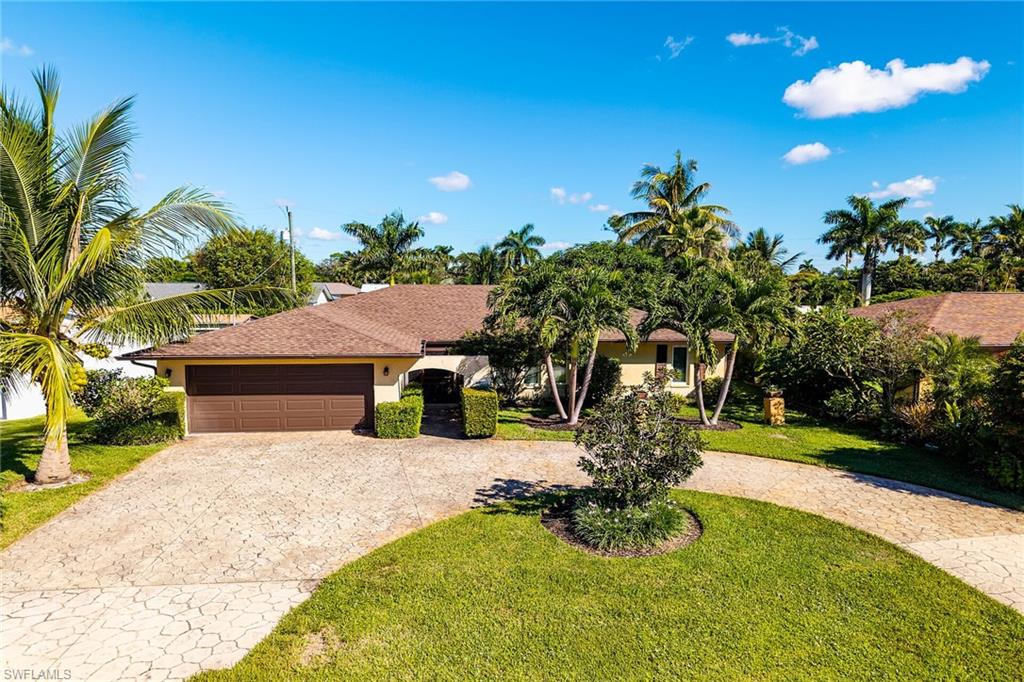 Ranch-style house featuring curved driveway, a front lawn, stucco siding, and a garage