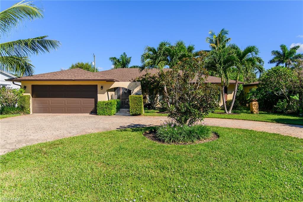 Ranch-style house featuring driveway, stucco siding, a front lawn, an attached garage, and roof with shingles