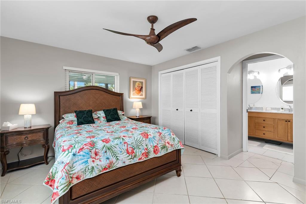 Bedroom with light tile patterned floors, a ceiling fan, ensuite bath, and a closet