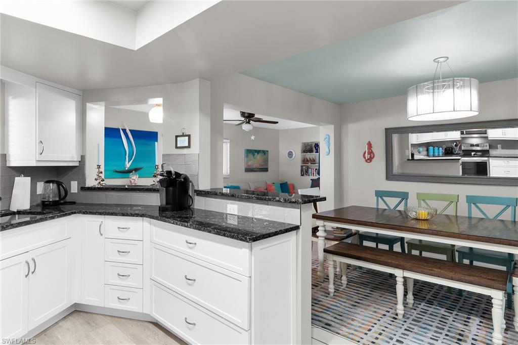 Kitchen with white cabinetry, stainless steel range with electric cooktop, backsplash, dark stone countertops, and a ceiling fan