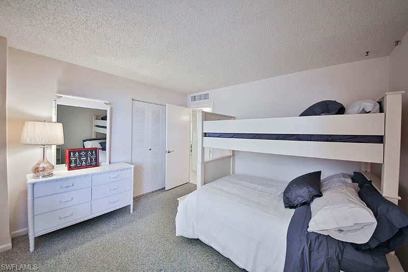 Bedroom featuring carpet flooring, a textured ceiling, and a closet