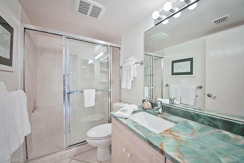 Full bath featuring vanity, light tile patterned floors, and a stall shower
