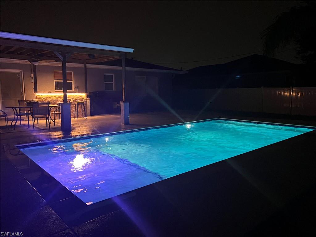 Pool at night featuring a patio area