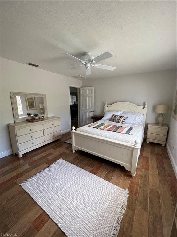 Bedroom featuring a textured ceiling, dark wood finished floors, and a ceiling fan