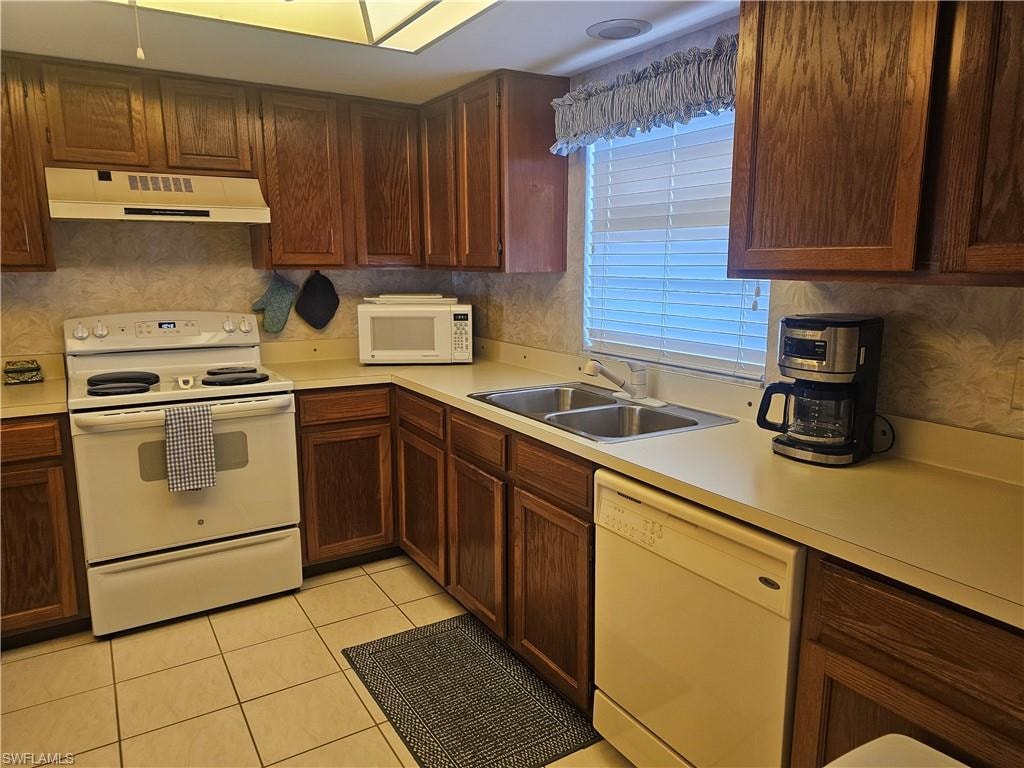 Kitchen with white appliances, light countertops, light tile patterned flooring, and ventilation hood