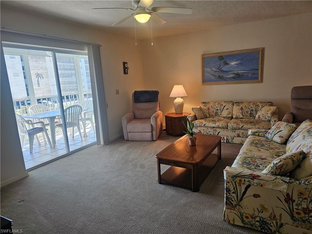 Carpeted living area featuring ceiling fan and a textured ceiling