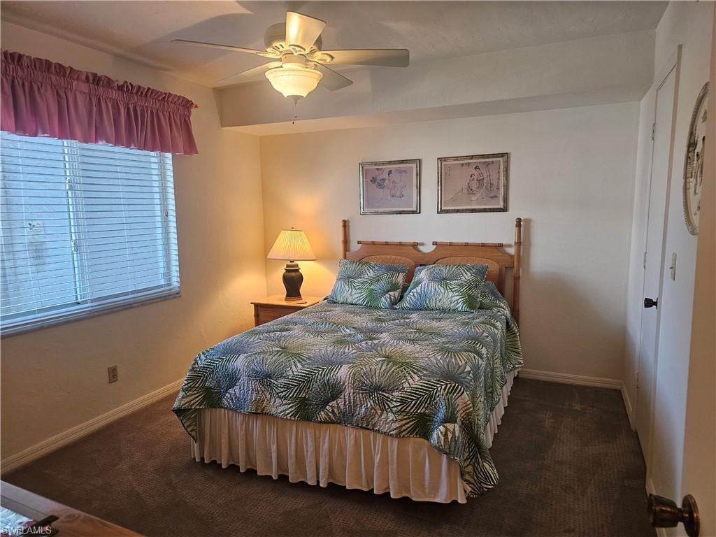 Bedroom with dark carpet and a ceiling fan