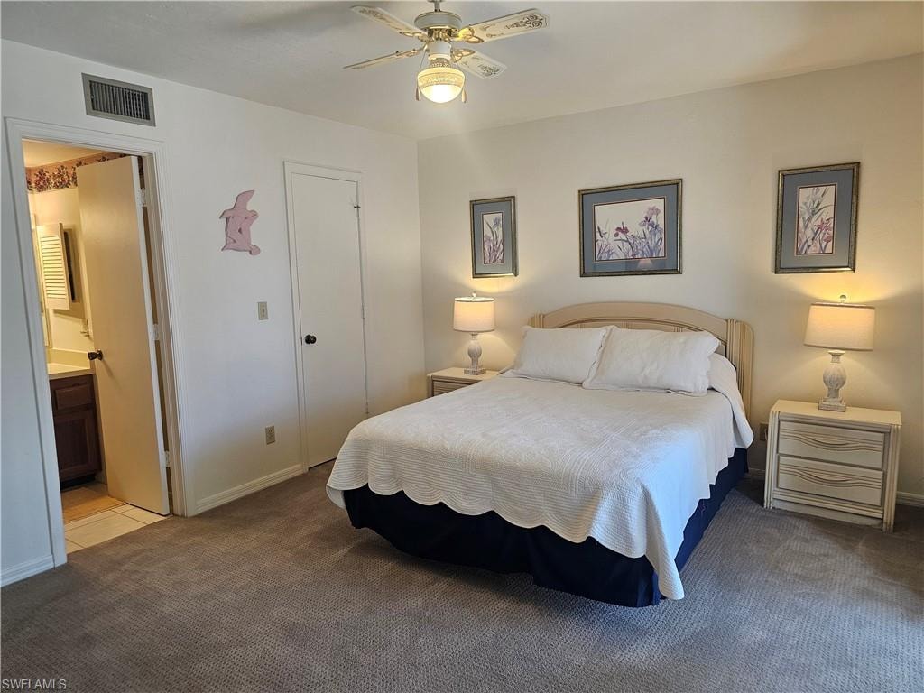 Carpeted bedroom featuring a ceiling fan and ensuite bathroom