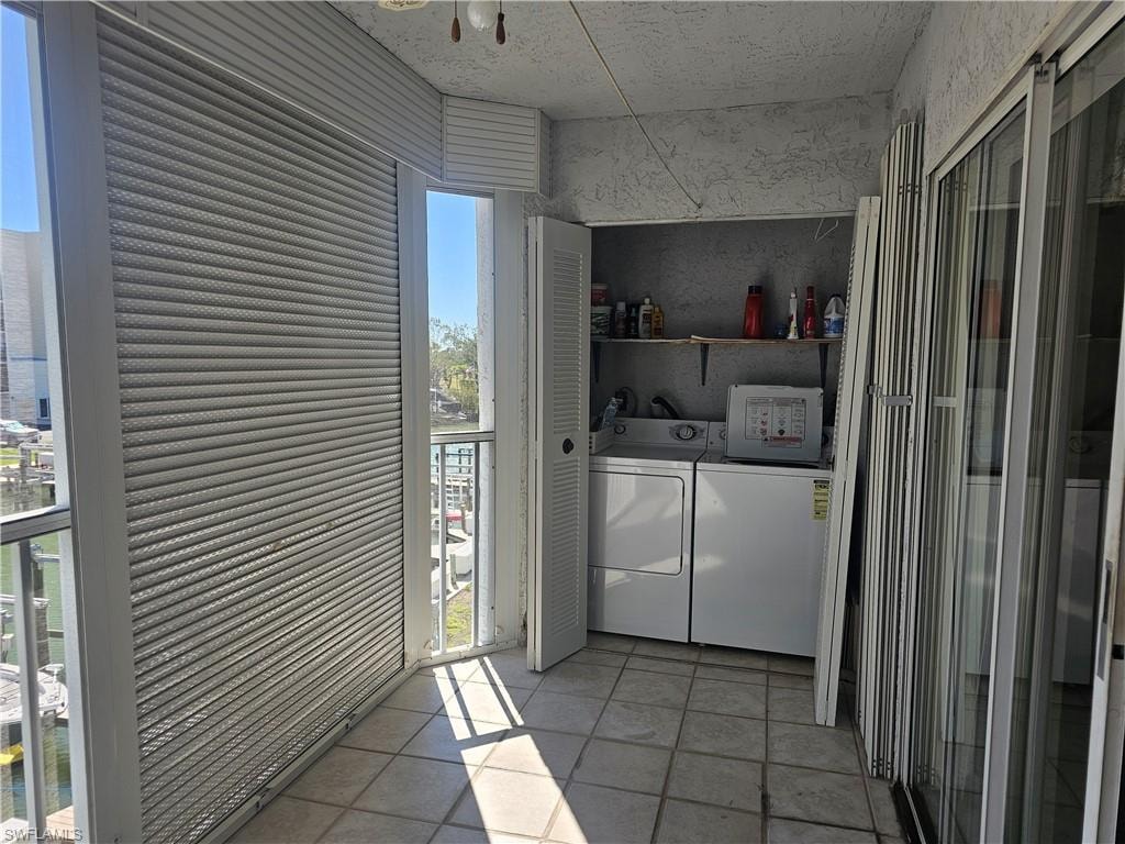 Laundry area with washing machine and clothes dryer and light tile patterned floors