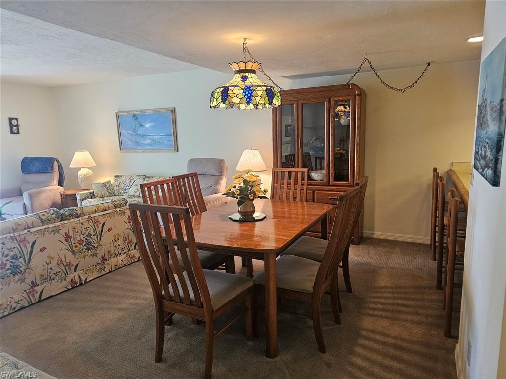 Dining area featuring dark carpet and a textured ceiling