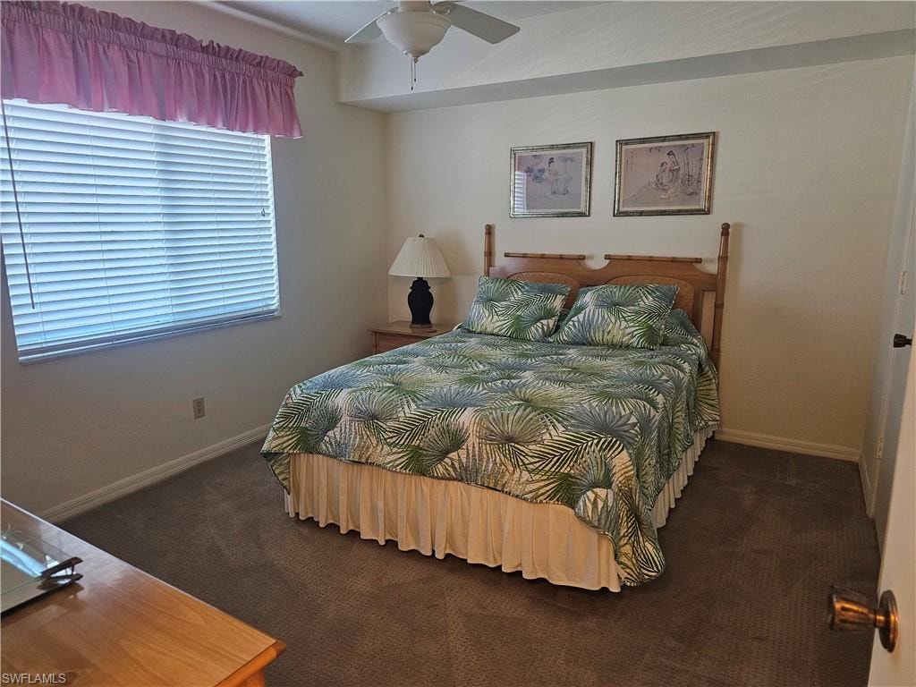 Carpeted bedroom with ceiling fan and baseboards