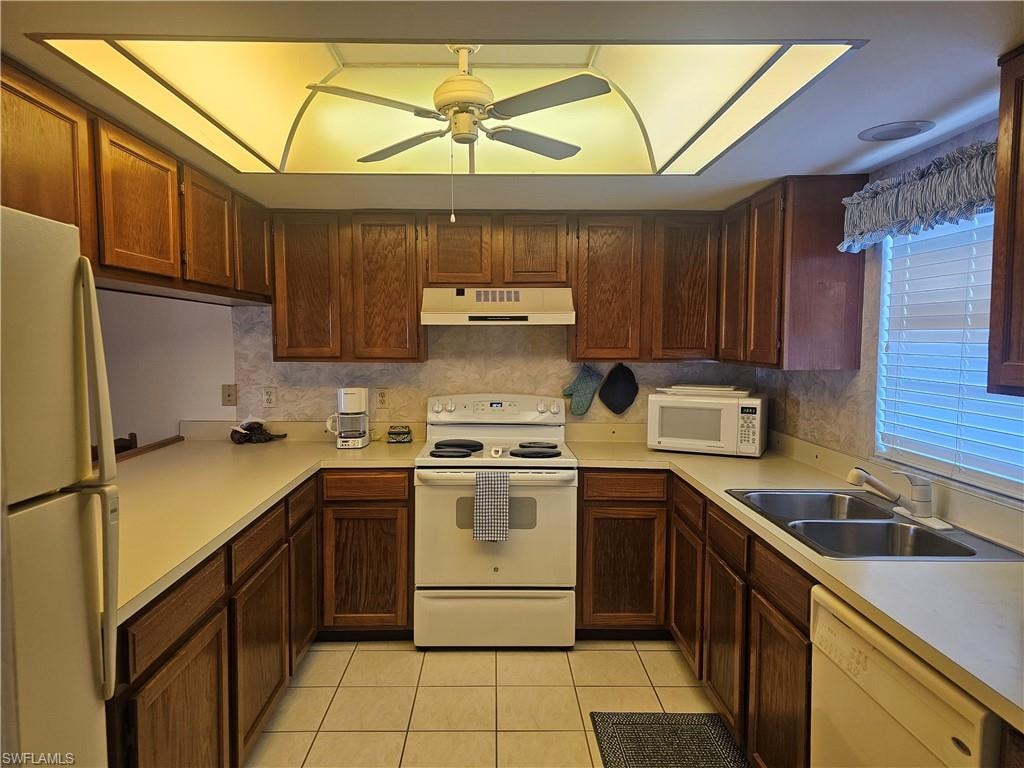 Kitchen featuring white appliances, light countertops, a ceiling fan, light tile patterned floors, and exhaust hood