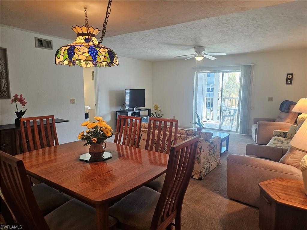 Carpeted dining area with a textured ceiling and ceiling fan