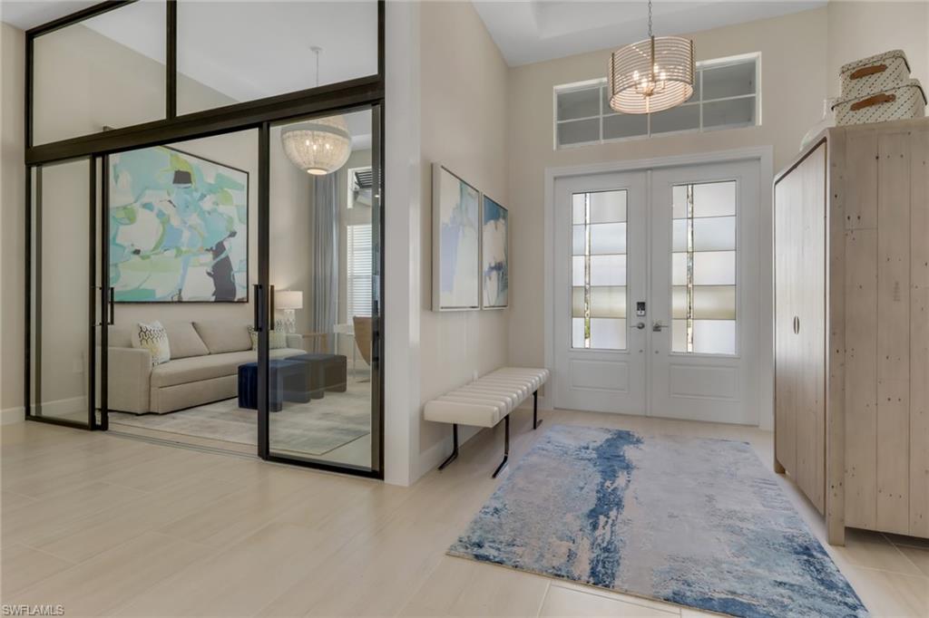 Doorway featuring french doors, a chandelier, plenty of natural light, and a towering ceiling