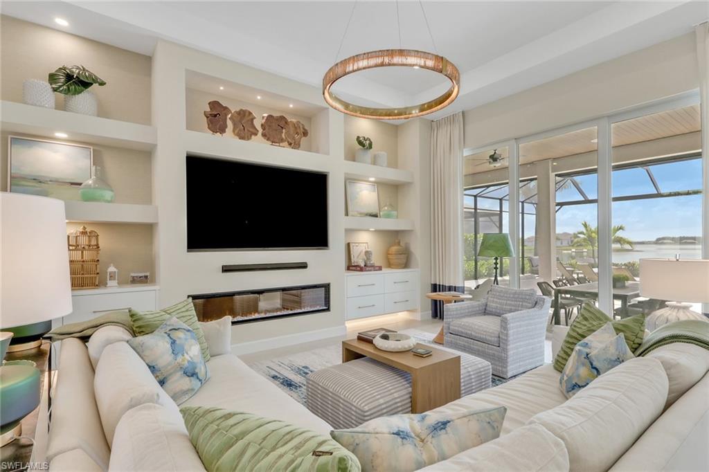 Living room with built in features, a sunroom, and a glass covered fireplace