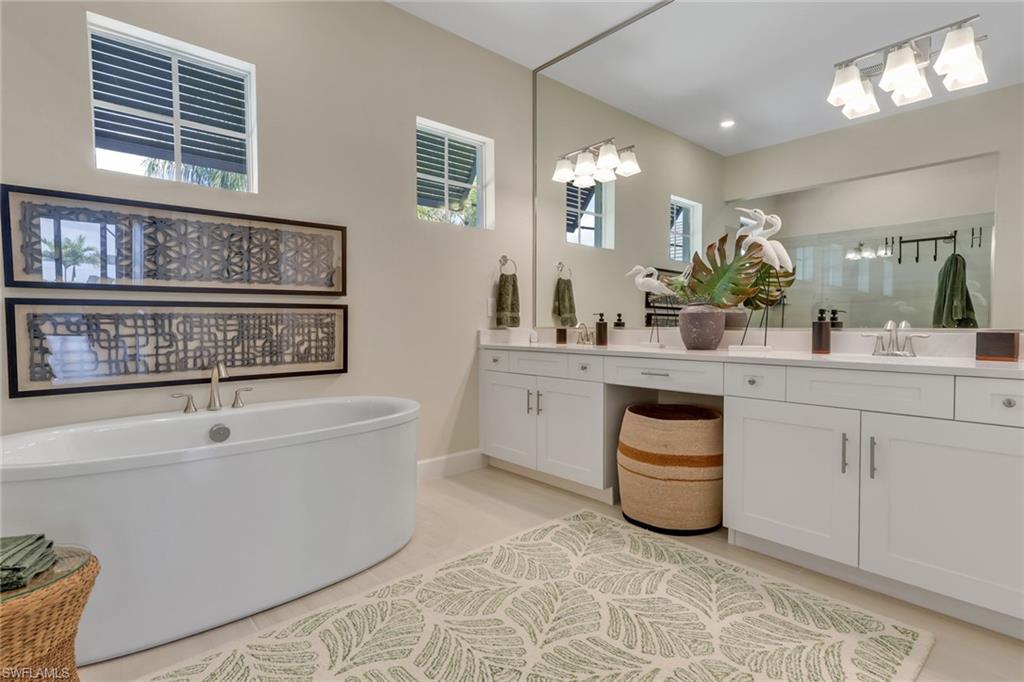 Full bathroom featuring double vanity, a shower stall, a soaking tub, and light tile patterned floors