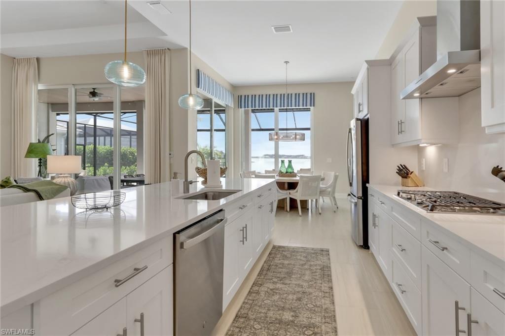 Kitchen featuring white cabinetry, wall chimney exhaust hood, and plenty of natural light