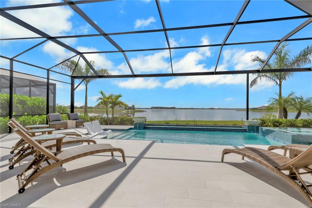 View of swimming pool with a sunroom, glass enclosure, a pool with connected hot tub, a patio area, and a water view
