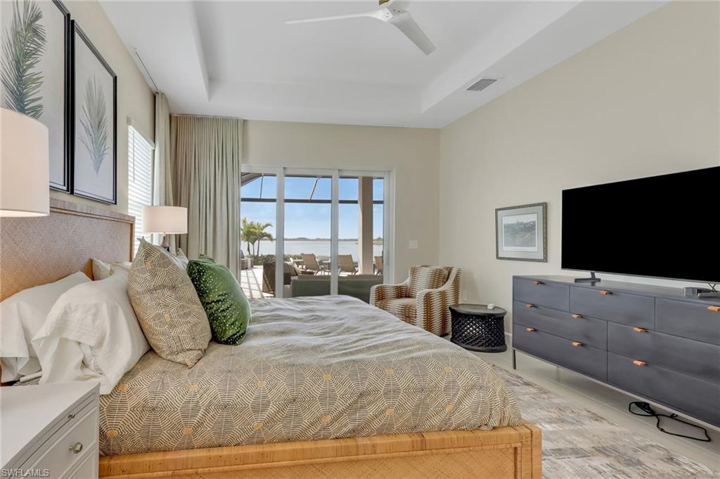 Bedroom with access to outside, a tray ceiling, and a ceiling fan
