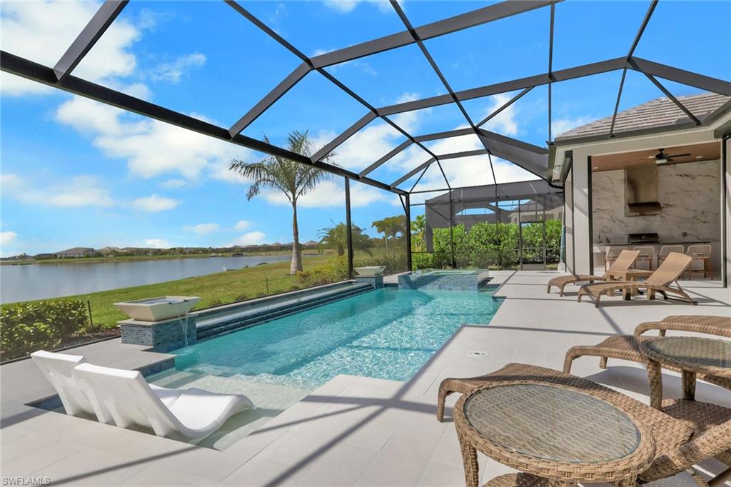View of pool with a ceiling fan, a lanai, a patio area, a sunroom, and a water view