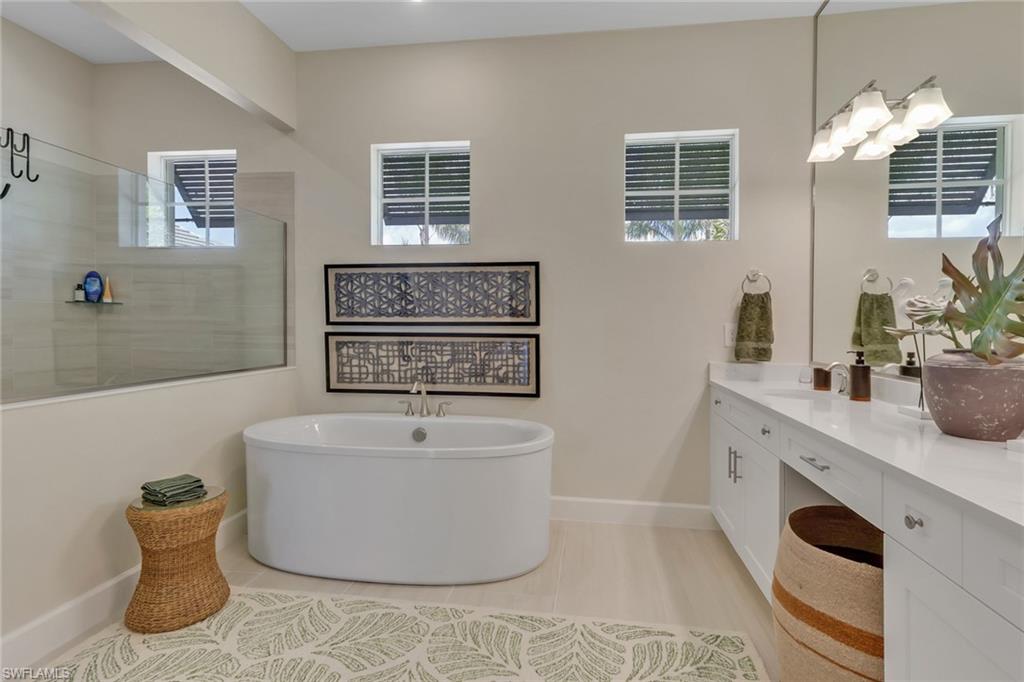 Full bath featuring a freestanding bath, vanity, a walk in shower, and light tile patterned floors
