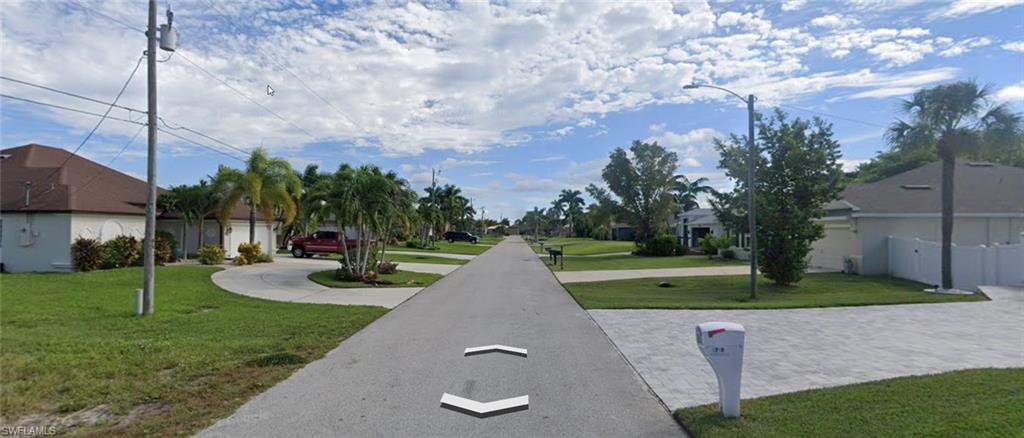 View of asphalt road featuring street lights and a residential view