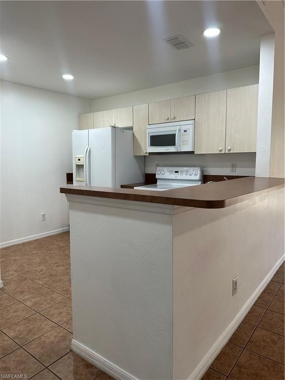 Kitchen featuring kitchen peninsula, refrigerator, white range, and dark tile patterned floors