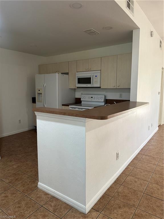 Kitchen with kitchen peninsula, cream cabinets, tile patterned floors, electric stove, and fridge