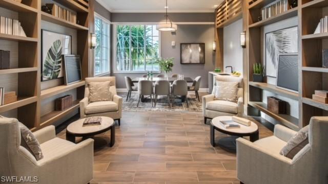 Sitting room with wood-type flooring and crown molding