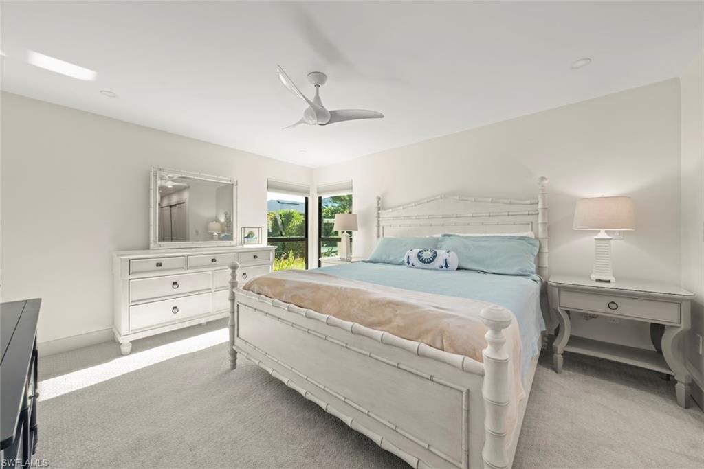 Carpeted bedroom with ceiling fan and baseboards